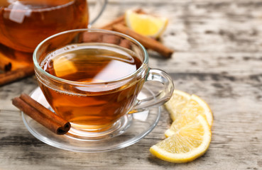 Cup with aromatic hot cinnamon tea and lemon on wooden table