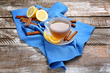 Cup with aromatic hot cinnamon tea and lemon on wooden table