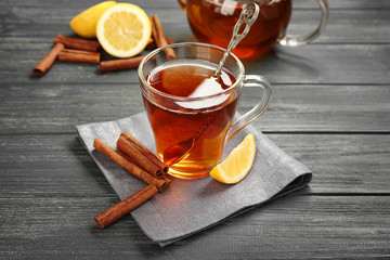 Cup with aromatic hot cinnamon tea and lemon on wooden table