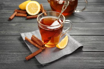 Papier Peint photo Theé Cup with aromatic hot cinnamon tea and lemon on wooden table