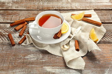 Cup with aromatic hot cinnamon tea and lemon on wooden table