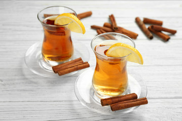 Two glass cups with aromatic hot cinnamon tea and lemon on wooden table