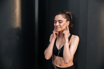 Happy young sports lady standing with earphones