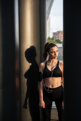 Serious young sports lady standing with earphones