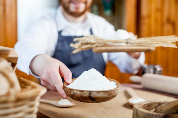 Man holding wheat flour in a bakery close up