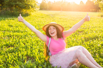Beautiful young laughing naughty woman sitting on the grass and smiling
