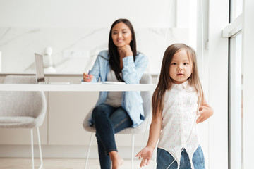 Little cute asian girl playing while her mother is working