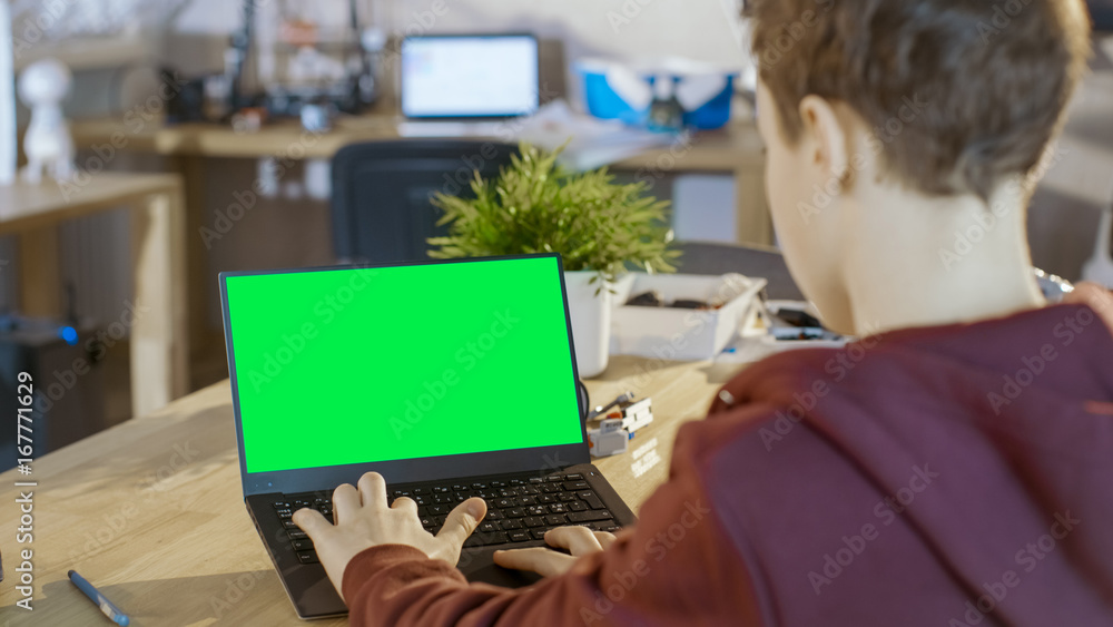 Aufkleber smart boy uses laptop with mock-up green screen in his computer science class.