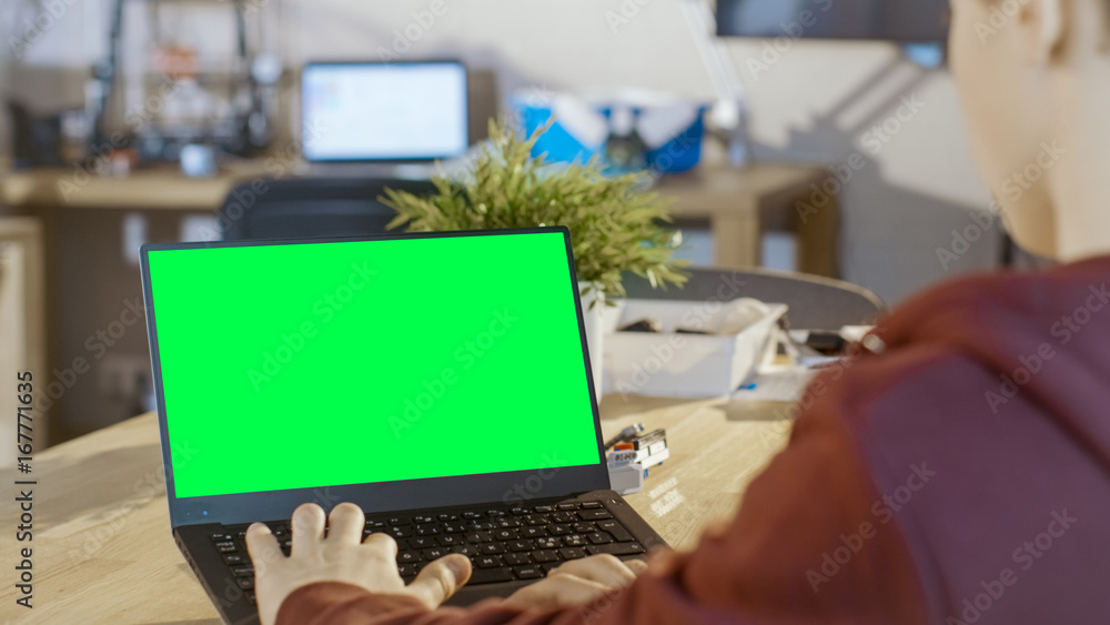 Poster smart boy uses laptop with mock-up green screen in his computer science class.