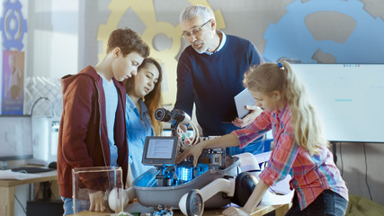 Teacher and His Pupils Work on a Programable Robot with LED Illumination for School Science Class...