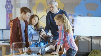 Teacher and His Pupils Work on a Programable Robot with LED Illumination for School Science Class Project.