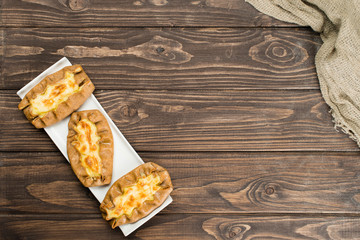 classical Italian fresh homemade Karelian pies with potato, carrot and rice on brown wooden background. Italian pastry, top view, copyspace for text