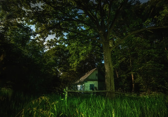 Old abandoned rural house in the backwoods. Night photo.
