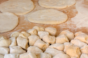 Fototapeta na wymiar Raw pizza dough with flour on wooden table.