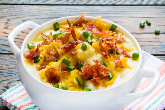 Easy homemade cheesy potato soup with bacon in a white bowl  on the wooden rustic table.