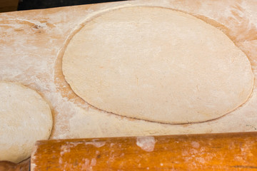 Rolled out pizza dough on floured surface.