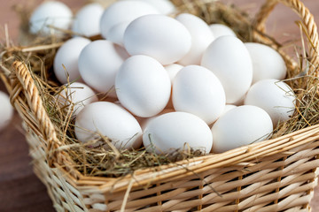 Chicken eggs in basket on wooden background