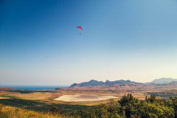 Paraglider flying over a valley.