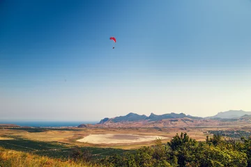 Photo sur Plexiglas Sports aériens Parapente survolant une vallée.