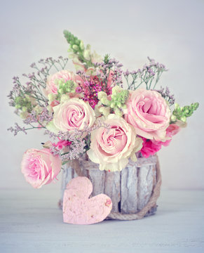 Close-up floral composition with a pink roses .Beautiful bouquet for a birthday or Valentine's Day.Congratulation with a flowers in a pot decorated with a heart. 