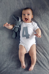 newborn to four months lying on the bed with the number four and the hare toy