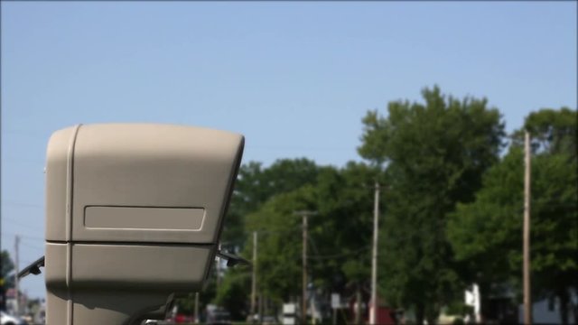 Generic modern tan mailbox alongside highway in suburban community