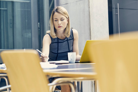 Young businesswoman writing at office desk