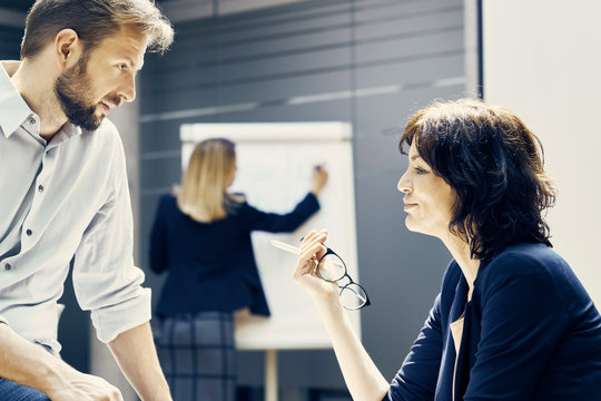 Businesswoman and man having discussion during office presentation