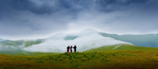 Hiking campers photographing a natural phenomenon - the clouds that roam the mountains. Concept theme: nature, weather, tourism, extreme, healthy lifestyle, adventures. Unrecognizable persones.