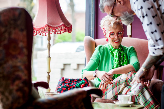 Quirky vintage man pouring tea for mature girlfriend in tea room