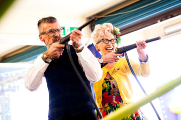 Quirky couple enjoying shooting gallery in amusement arcade, Bournemouth, England