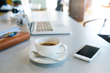 Office desk with coffee cup, smartphone and laptop.