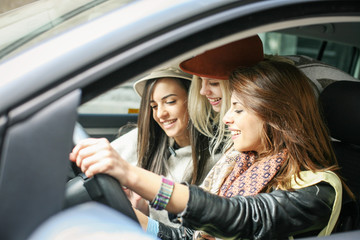 Fototapeta na wymiar Three girls in the car. Girls can drive the car through the city