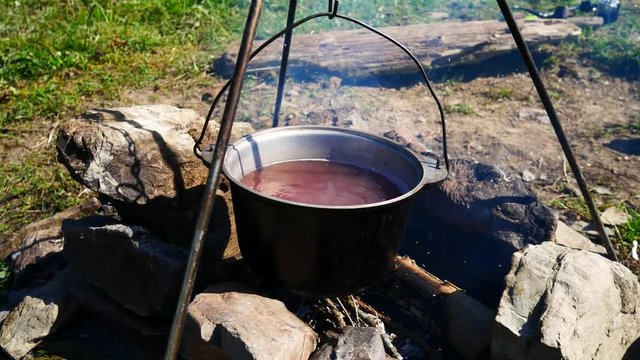 Bowler at the stake. Pot stands on fire, cooking food in the camp.