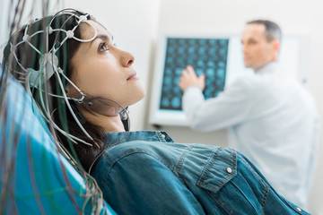 Charming young woman undergoing electroencephalography - obrazy, fototapety, plakaty