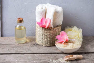 Sea salt in bowl, towels, bottles with aroma oil and flowers on  wooden  background.