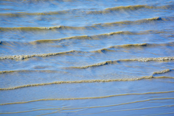 Small waves of the sea surf with muddy water