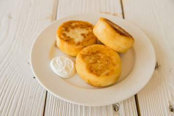 Cottage cheese cakes on plate with sour cream