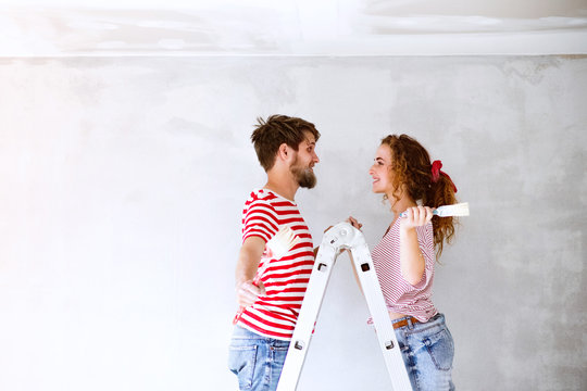 Young couple painting walls in their new house.