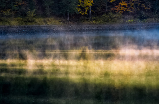 foggy surface of the forest lake at sunrise