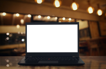 open laptop with white screen on wooden table in front of abstract blurred restaurant lights background.