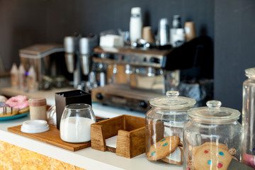 Bar counter with biscuits, donuts and sugar in the coffee house, against the background of the coffee machine - obrazy, fototapety, plakaty