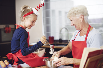 Cute girl cooking with help of her grandmother