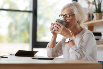Joyful elderly woman enjoying her tea
