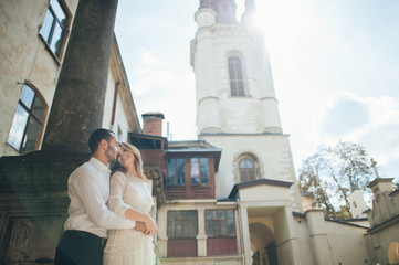 full length of couple posing near church in old town
