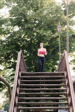 Young female runner running across footbridge