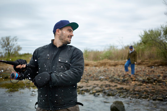 Young man getting splashed by sea while sea fishing