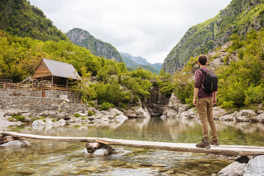 Man on wooden bridge looking at cabin, Accursed mountains, Theth, Shkoder, Albania, Europe
