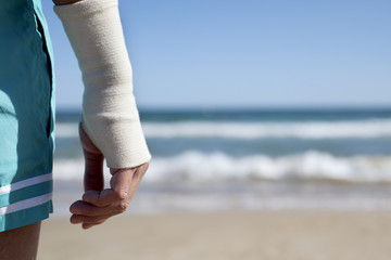 man on the beach with a bandage in his wrist - obrazy, fototapety, plakaty