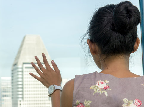 A woman looks over the city from the observation cabin.  View from Ferris wheel. A girl looks out the window at the skyscrapers.